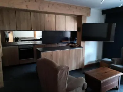 a kitchen with wooden cabinets and a flat screen tv at Résidence La Ginabelle - maeva Home - 4 Pièces 6 Personnes - Prestige MAE-1506 in Chamonix-Mont-Blanc