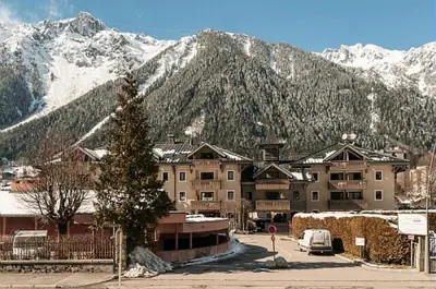 a large building in front of a snow covered mountain at Résidence La Ginabelle - maeva Home - 4 Pièces 6 Personnes Sélection MAE-5671 in Chamonix-Mont-Blanc