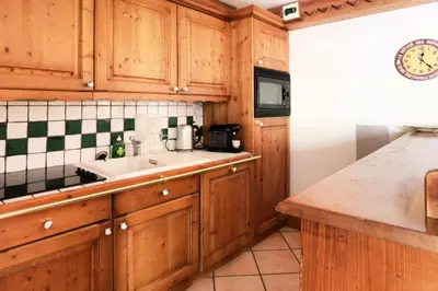a kitchen with wooden cabinets and a sink at Résidence La Ginabelle - maeva Home - 4 Pièces 6 Personnes Sélection MAE-5671 in Chamonix-Mont-Blanc