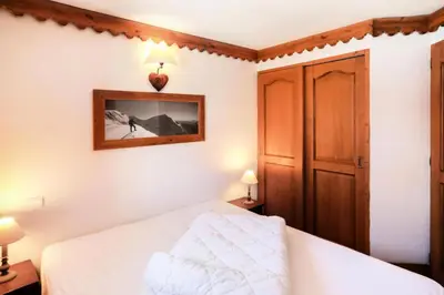 a bedroom with a white bed and a wooden cabinet at Résidence La Ginabelle - maeva Home - 4 Pièces 6 Personnes Sélection MAE-5671 in Chamonix-Mont-Blanc