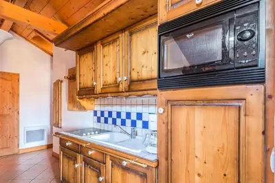 a kitchen with wooden cabinets and a sink and a microwave at Résidence Les Fermes du Soleil - maeva Home - Appartement 4 pièces 7 personnes Selection MAE-0493 in Les Carroz d'Araches