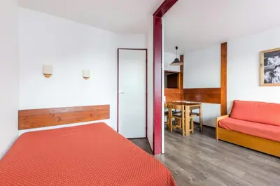 a bedroom with a red bed and a table at L'Aiguille - maeva Home - Appartement 2 pièces 5 personnes Confort MAE-7119 in Chamonix-Mont-Blanc