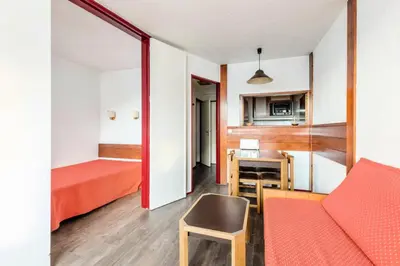 a small room with a red bed and a kitchen at L'Aiguille - maeva Home - Appartement 2 pièces 5 personnes Confort MAE-7119 in Chamonix-Mont-Blanc