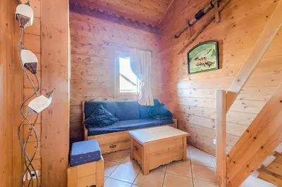 a room with a blue couch in a wooden cabin at Résidence Les Fermes du Soleil - maeva Home - 3 pièces 6 pers Sélection MAE-5543 in Les Carroz d'Araches