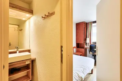 a bathroom with a bed and a sink and a mirror at L'Aiguille - maeva Home - 2 Pièces 5 Personnes Sélection MAE-1179 in Chamonix-Mont-Blanc