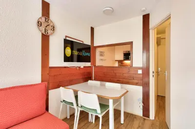 a dining room with a table and chairs and a clock at L'Aiguille - maeva Home - 2 Pièces 5 Personnes Sélection MAE-1179 in Chamonix-Mont-Blanc