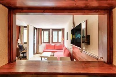 a living room with a red couch and a table at L'Aiguille - maeva Home - 2 Pièces 5 Personnes Sélection MAE-1179 in Chamonix-Mont-Blanc