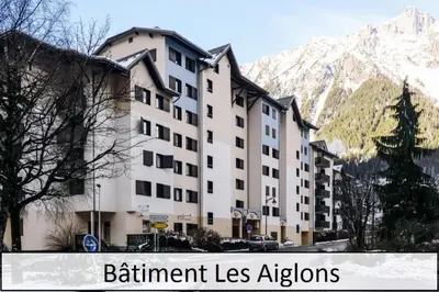 a building in front of a mountain with the words retirement lessensions at L'Aiguille - maeva Home - 2 Pièces 5 Personnes Confort MAE-2139 in Chamonix-Mont-Blanc