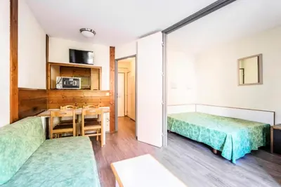 a room with two beds and a table and chairs at L'Aiguille - maeva Home - 2 Pièces 5 Personnes Confort MAE-2139 in Chamonix-Mont-Blanc
