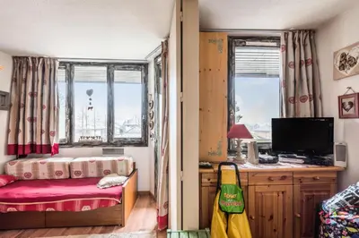 a bedroom with a bed and a tv and windows at L'Aiguille - maeva Home - Appartement 2 pièces 5 personnes Confort MAE-2592 in Chamonix-Mont-Blanc