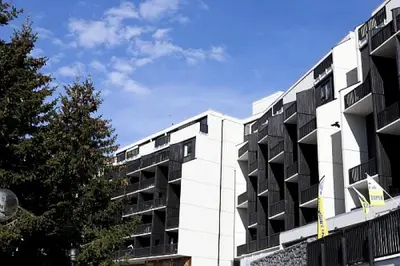 a white building with black balconies next to a tree at Résidence La Forêt - maeva Home - Appartement 2 Pièces 5 Personnes - Confort MAE-4236 in Flaine