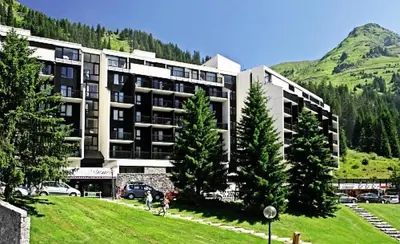 a large building with trees in front of a mountain at Résidence La Forêt - maeva Home - Appartement 2 Pièces 5 Personnes - Confort MAE-4236 in Flaine