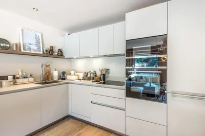 a white kitchen with white cabinets at Appartement du Cerf - Welkeys in Megève