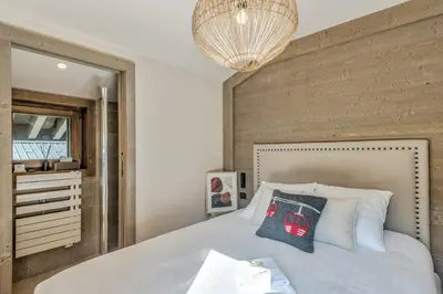 a bedroom with a bed and a chandelier at Appartement du Cerf - Welkeys in Megève