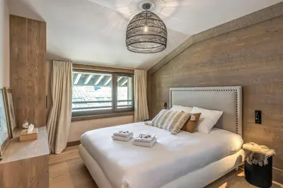 a bedroom with a large white bed and a window at Appartement du Cerf - Welkeys in Megève