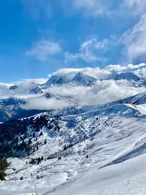 a mountain covered in snow with clouds in the background at Residence le Grand Panorama - with garden & view in Saint-Gervais-les-Bains