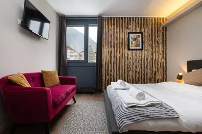 a bedroom with a bed and a red chair and a window at Beautiful cosy, modern studio in Chamonix centre in Chamonix-Mont-Blanc