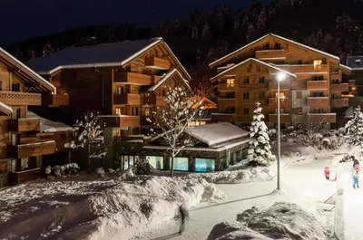 a lodge in the snow with people walking in front of it at Résidence Les Fermes du Soleil - maeva Home - Appartement 3 pièces 6 personnes - Prestige MAE-0374 in Les Carroz d'Araches