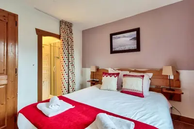 a bedroom with a large bed with red and white pillows at Résidence Les Fermes du Soleil - maeva Home - Appartement 3 pièces 6 personnes - Prestige MAE-0374 in Les Carroz d'Araches