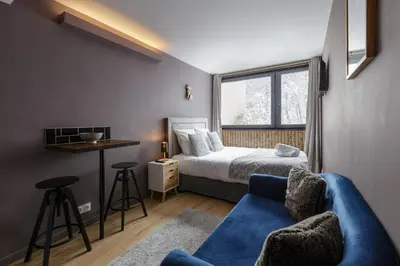 a bedroom with a bed and a blue couch at Beautiful mountain view studio by the lake in Chamonix-Mont-Blanc