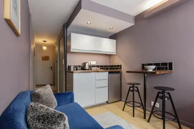 a living room with a blue couch and a kitchen at Beautiful mountain view studio by the lake in Chamonix-Mont-Blanc