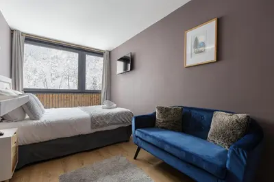 a bedroom with a bed and a blue couch at Beautiful mountain view studio by the lake in Chamonix-Mont-Blanc