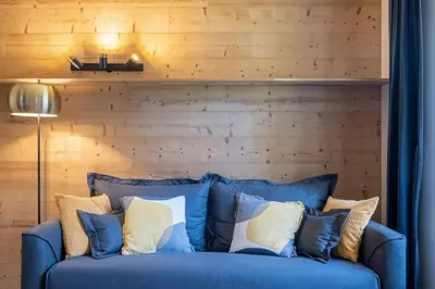 a blue couch with pillows in front of a wooden wall at La Rose de Glace in Chamonix-Mont-Blanc
