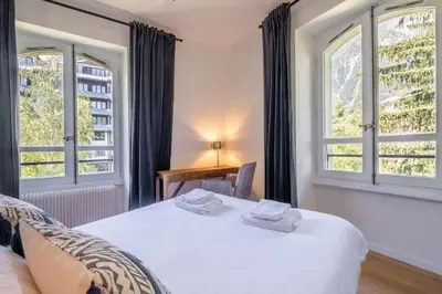 a bedroom with a white bed and two windows at La Rose de Glace in Chamonix-Mont-Blanc