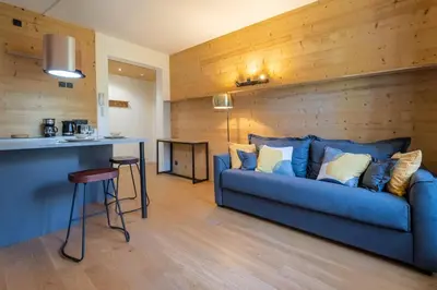 a living room with a blue couch and a kitchen at La Rose de Glace in Chamonix-Mont-Blanc