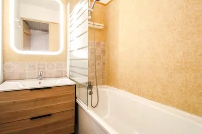 a bathroom with a tub and a sink and a mirror at Studio Cabine Sud, centre de Flaine, linge et menage compris in Flaine