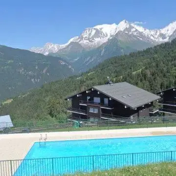 a house with a swimming pool in front of a mountain at LE GL'ASSIE in Saint-Gervais-les-Bains