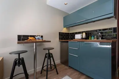 a kitchen with blue cabinets and two bar stools at Modern apartment with the best Mont Blanc view! in Chamonix-Mont-Blanc