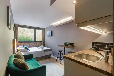 a kitchen with a couch and a bed in a room at Fantastic studio by the lake with Mountain View in Chamonix-Mont-Blanc