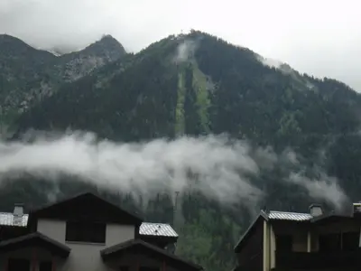 a mountain obscured by clouds with houses in the foreground at Appartment Aiguille Du Midi in Chamonix-Mont-Blanc