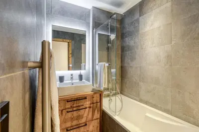 a bathroom with a sink and a tub and a mirror at Appartement 2 chambres en centre-ville de Megève in Megève
