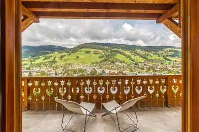 a balcony with two chairs and a view of a city at Appartement 2 chambres en centre-ville de Megève in Megève