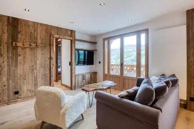 a living room with a couch and chairs and a tv at Appartement 2 chambres en centre-ville de Megève in Megève
