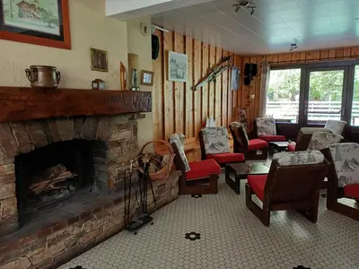 a living room with a stone fireplace and chairs at Hotel et centre de vacances Le Choucas in Sixt