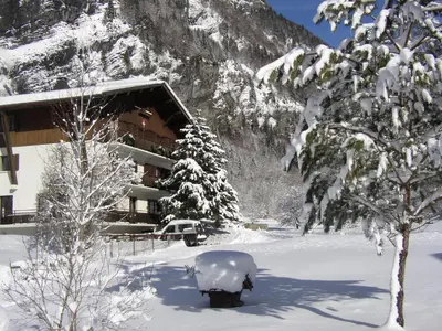 a snow covered building in front of a snow covered tree at Hotel et centre de vacances Le Choucas in Sixt