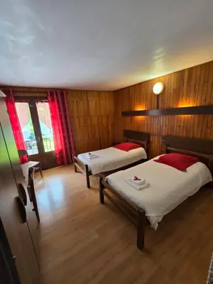 two beds in a room with wooden walls at Hotel et centre de vacances Le Choucas in Sixt