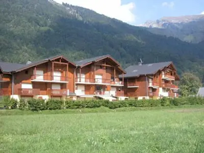 a large building in a field with a mountain at Duplex T4 calme avec parking, animaux acceptés à Samoëns - FR-1-629-133 in Samoëns