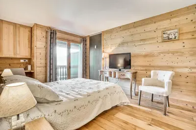 a bedroom with a bed and a desk and a television at Marmots in Megève