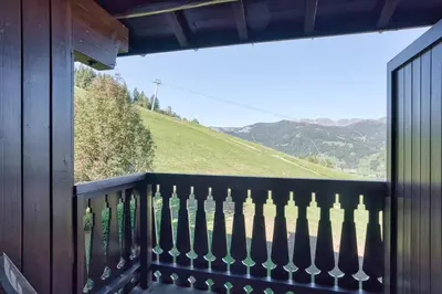 a balcony with a view of a green hill at Marmots in Megève