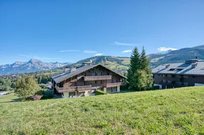 a house on a hill with mountains in the background at Marmots in Megève