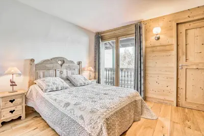 a bedroom with a bed and a large window at Marmots in Megève