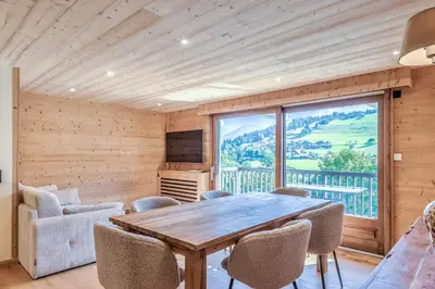 a dining room with a table and chairs and a large window at Appartement Chablis - Welkeys in Combloux