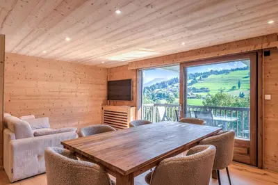 a room with a wooden table and chairs and a large window at Appartement Chablis - Welkeys in Combloux