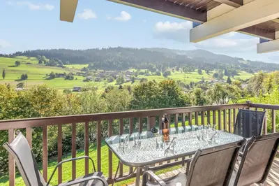 a table on a balcony with a view of the mountains at Appartement Chablis - Welkeys in Combloux