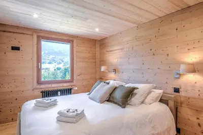 a bedroom with a bed with a wooden wall at Appartement Chablis - Welkeys in Combloux
