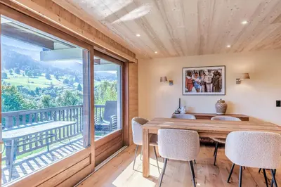 a dining room with a table and chairs and a large window at Appartement Chablis - Welkeys in Combloux